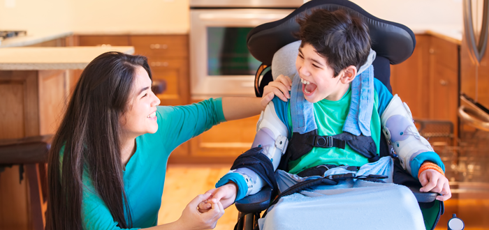 Mother smiling and laughing with an adolescent in a wheelchair